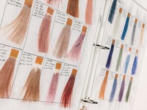 Professional hair color swatch book featuring blonde, brunette, red, and fashion color samples used by stylists for custom hair color matching at Garbo's Salon.