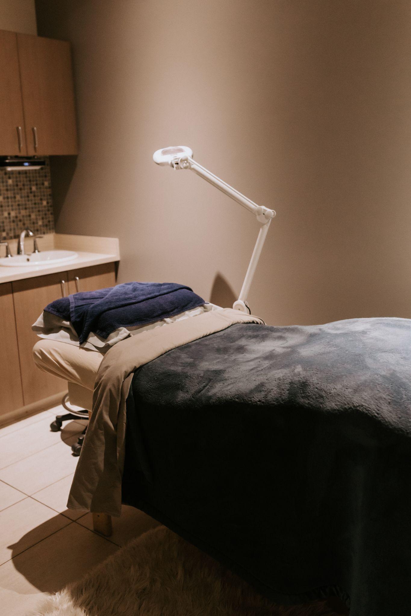 Spa treatment room with facial bed and lighted magnifier lamp